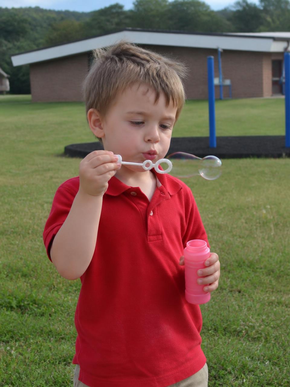 Illustration of a preschooler blowing bubbles on the playground