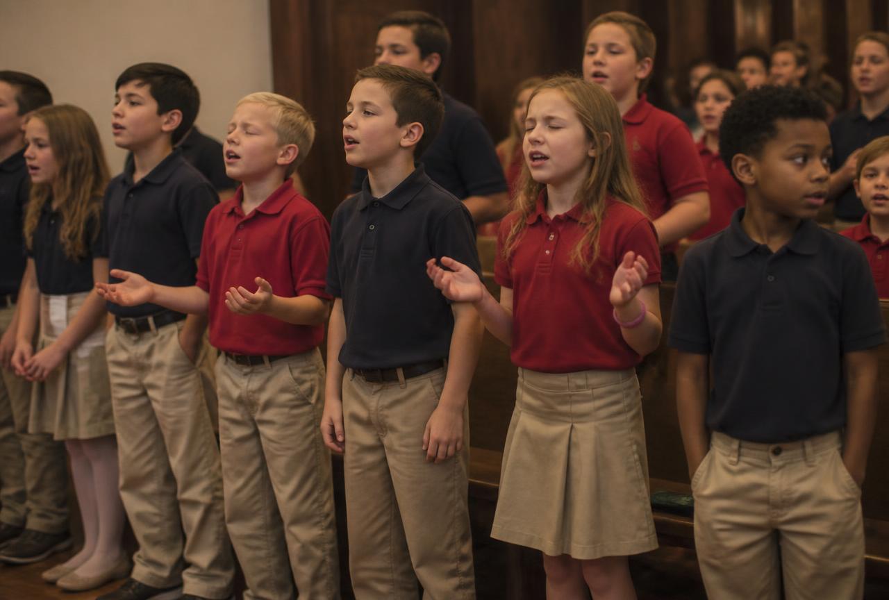 Illustration of students in the KCA chapel uniform — red or navy polos with khakis and khaki skorts — singing in chapel