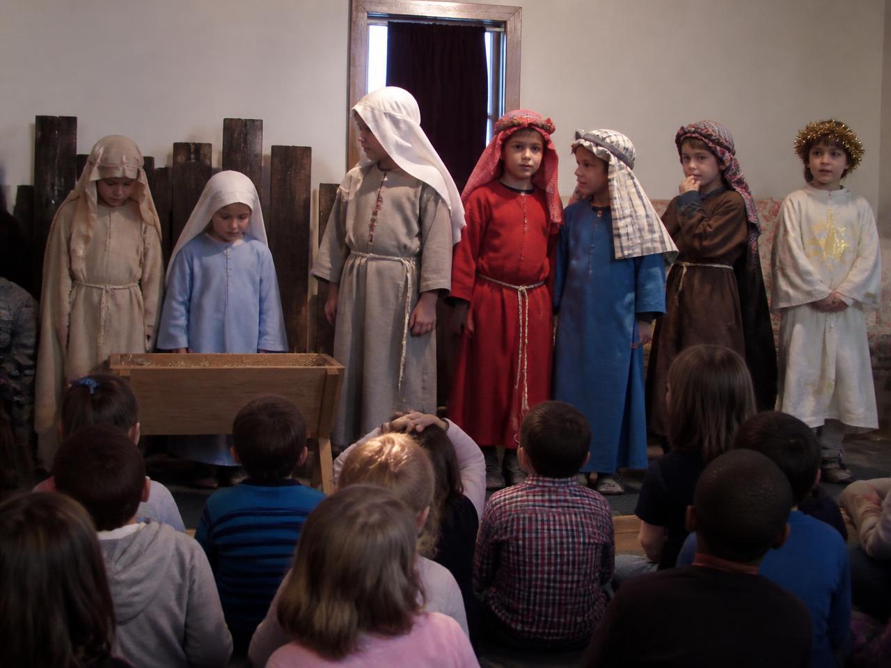 Illustration of students in costume performing the nativity story on stage while classmates watch