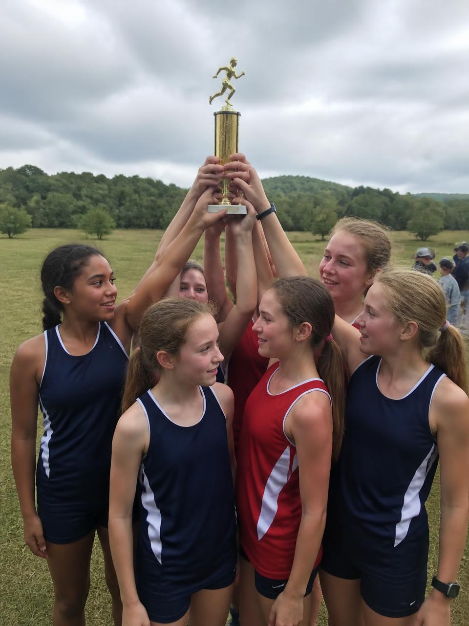 Illustration of a girls cross country team holding a team trophy overhead on the race field